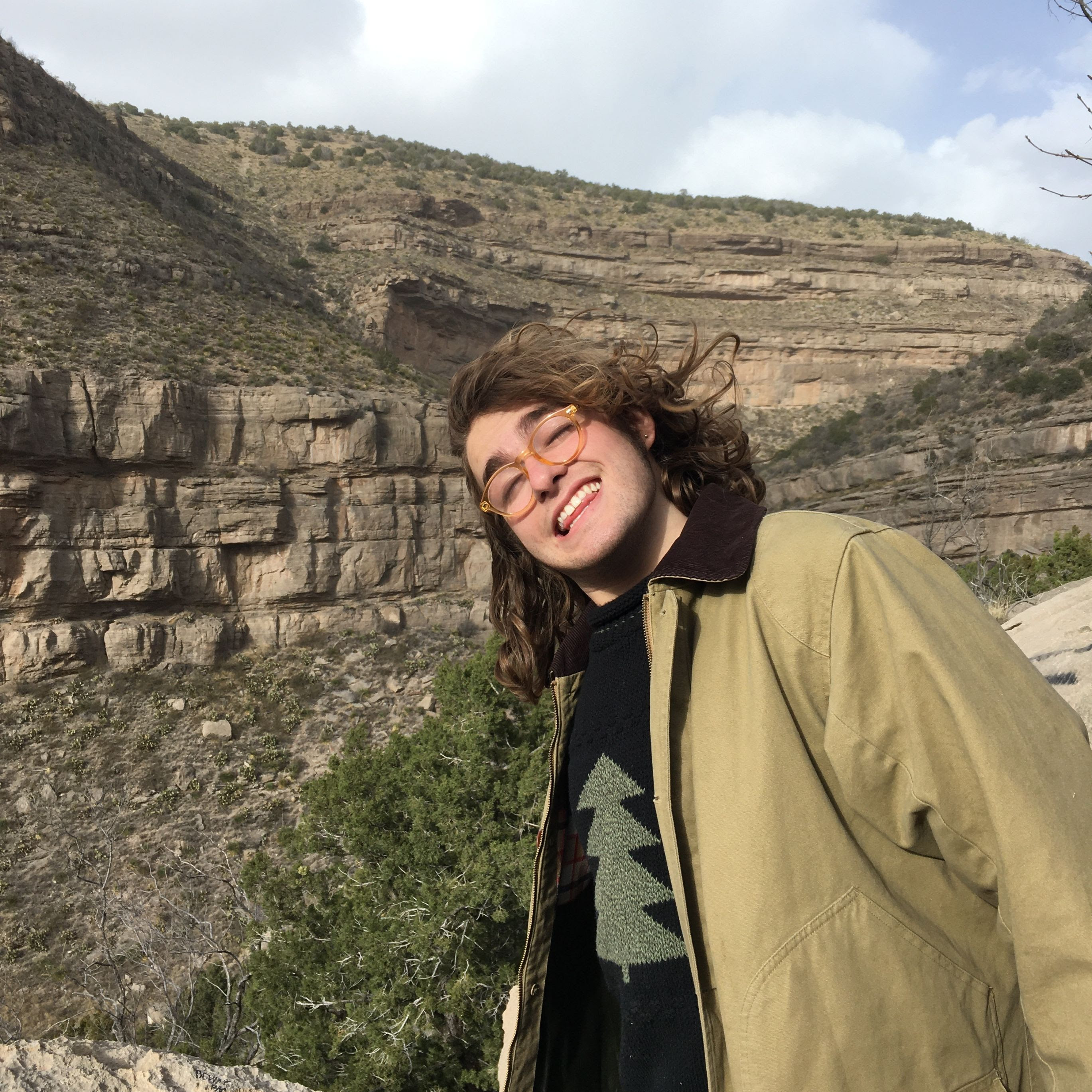 Burke Wood smiling in front of large mountain rock