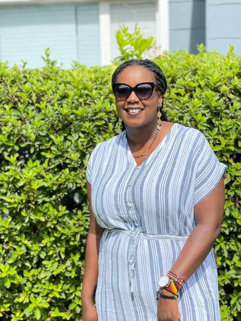 Diana Githu in front of a wall of leaves