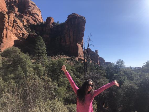 Jaden raising her hands in front of a large rock formation