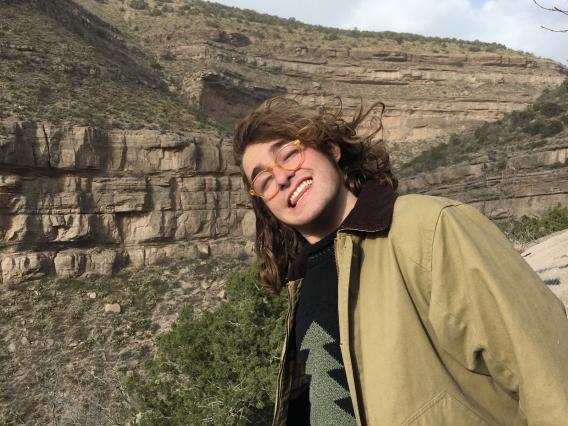 Burke Wood smiling in front of large mountain rock