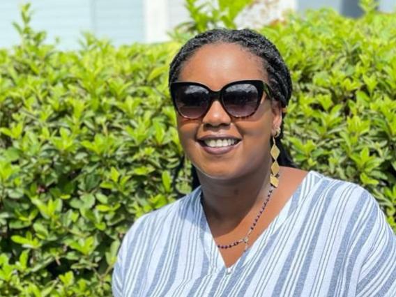 Diana Githu in front of a wall of leaves