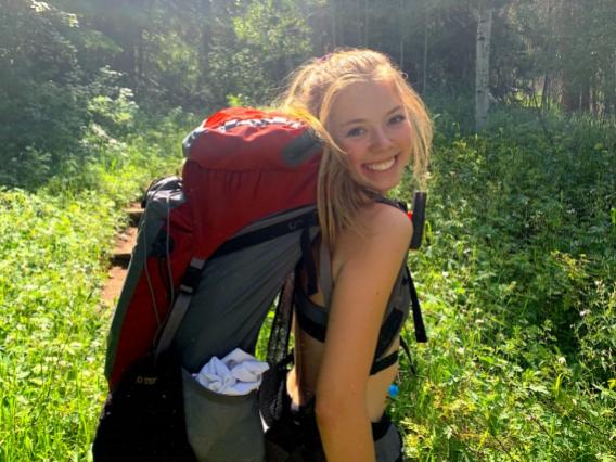 Jeri Wilcox with a backpacking pack on in a forest