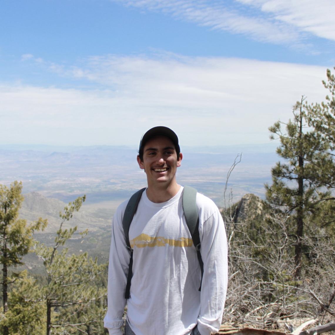 Aaron Nach standing in front of trees and mountains