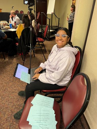 Maria Mata Robles holding a laptop during a conference panel