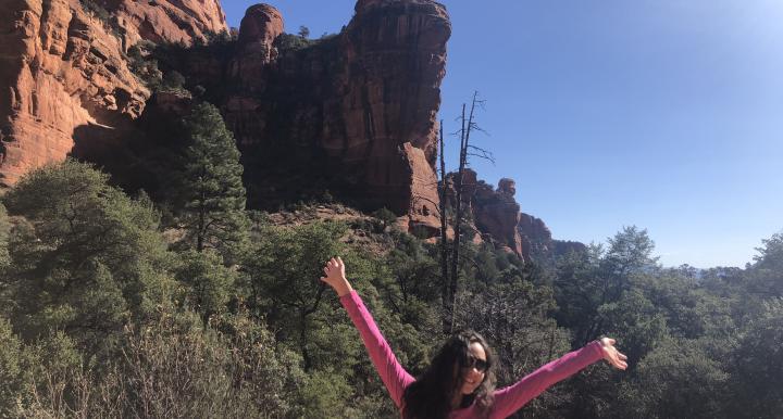 Jaden raising her hands in front of a large rock formation