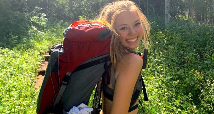 Jeri Wilcox with a backpacking pack on in a forest